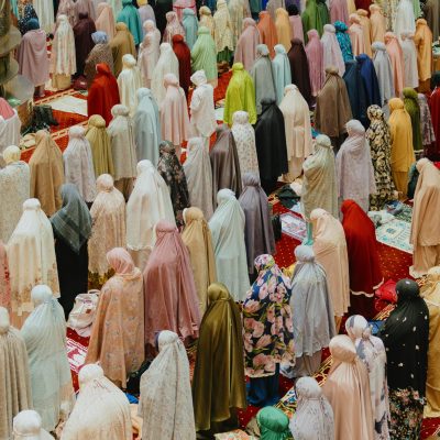 Muslim women praying in a Jakarta mosque, participating in a vibrant religious gathering.